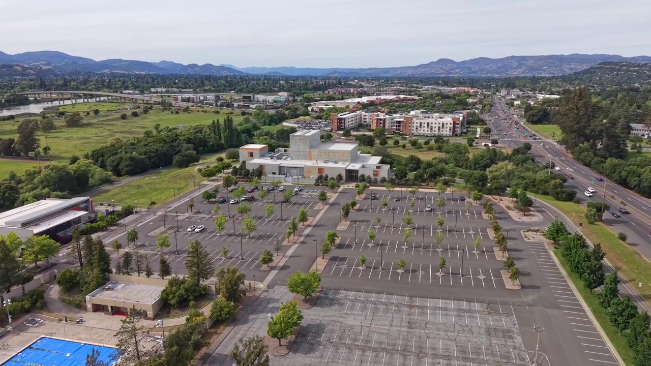 Vasto parcheggio vuoto ed edifici del campus del Napa Valley College in California, visti da una prospettiva aerea con un'autostrada e montagne distanti in una giornata nuvolosa