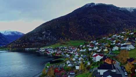 zoom in aerial shot of a town situated near a lake in norway mountain summits in the background