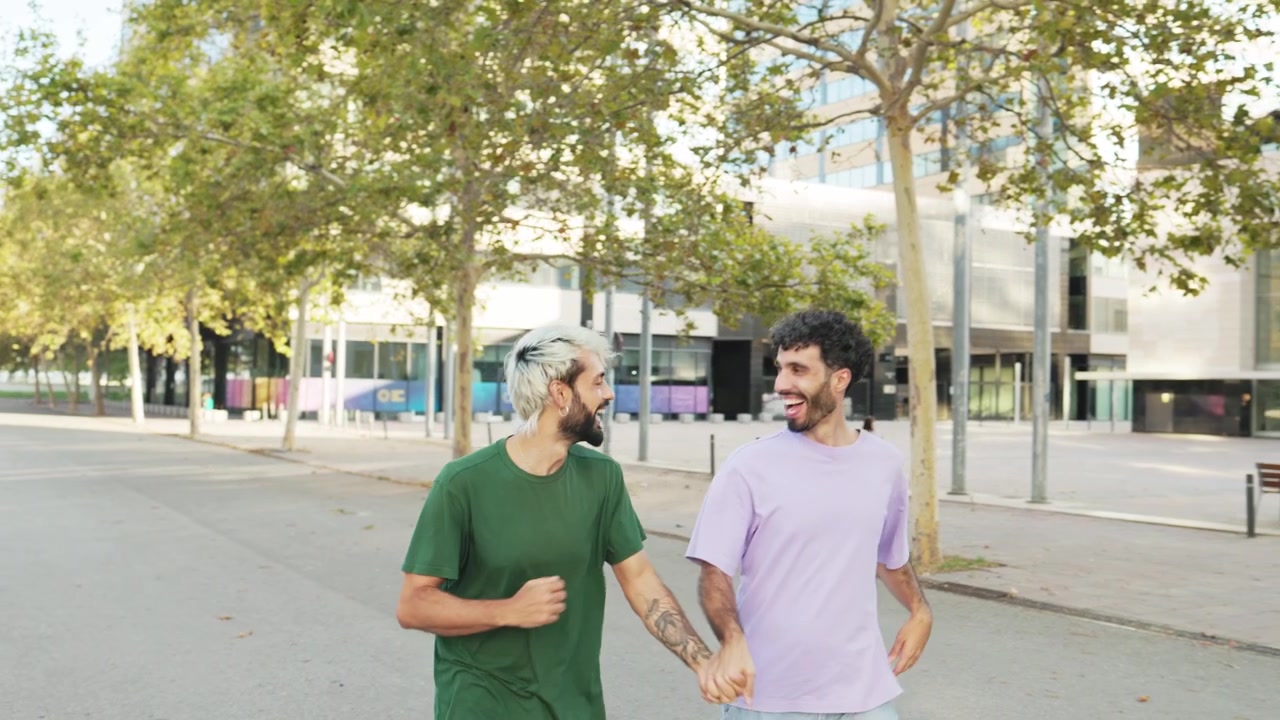 Casal gay feliz de mãos dadas e rindo enquanto caminha