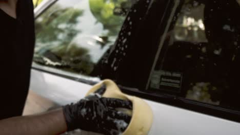 Primer-Plano-De-Un-Hombre-Lavando-Un-Auto-Usando-Guantes-Negros-Con-Champú-Y-Esponja