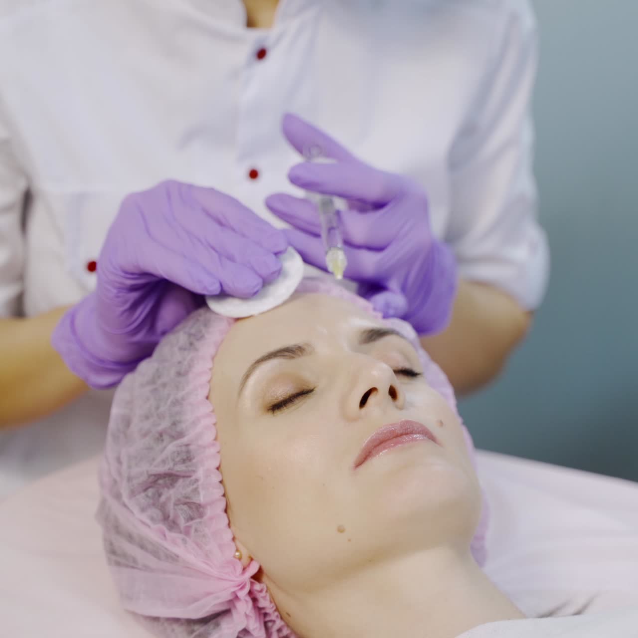 A specialist is making injections of mesotherapy to a client in the forehead area in the center of cosmetology. Modern cosmetology. Skin moisturizing procedure