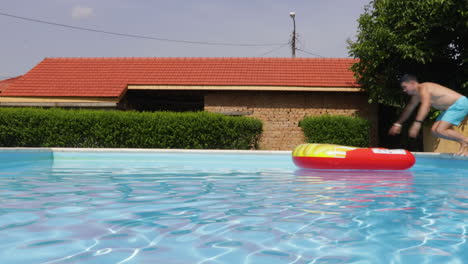 un hombre se sumerge en su flotador en una villa de piscina - toma estática
