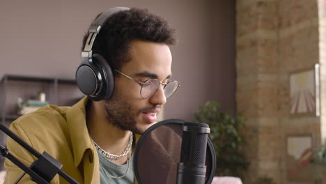 vista de cerca del hombre que usa anteojos mientras habla en un micrófono y graba un podcast