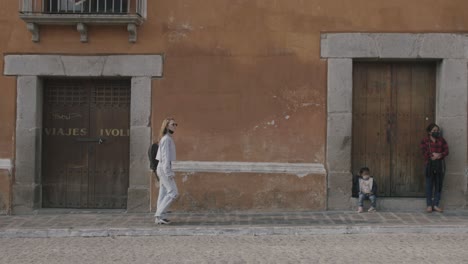 Wide-of-a-street-in-slow-motion-as-a-person-walks-across-frame-on-a-sidewalk-in-Antigua,-Guatemala