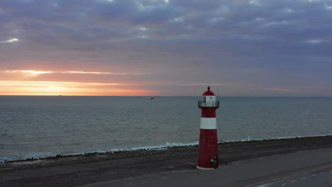 the lighthouse of westkapelle during a bright orange sunset, with a lot of wind