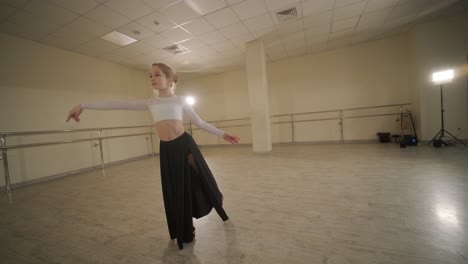 a group of young ballet students in black dancewear practicing positions in a spacious ballet studio with wooden flooring and wall-mounted barres. focused expressions and synchronized movements.