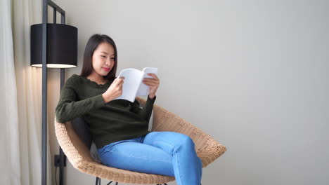 beautiful asian woman sitting reading a book under a lamp, smiling