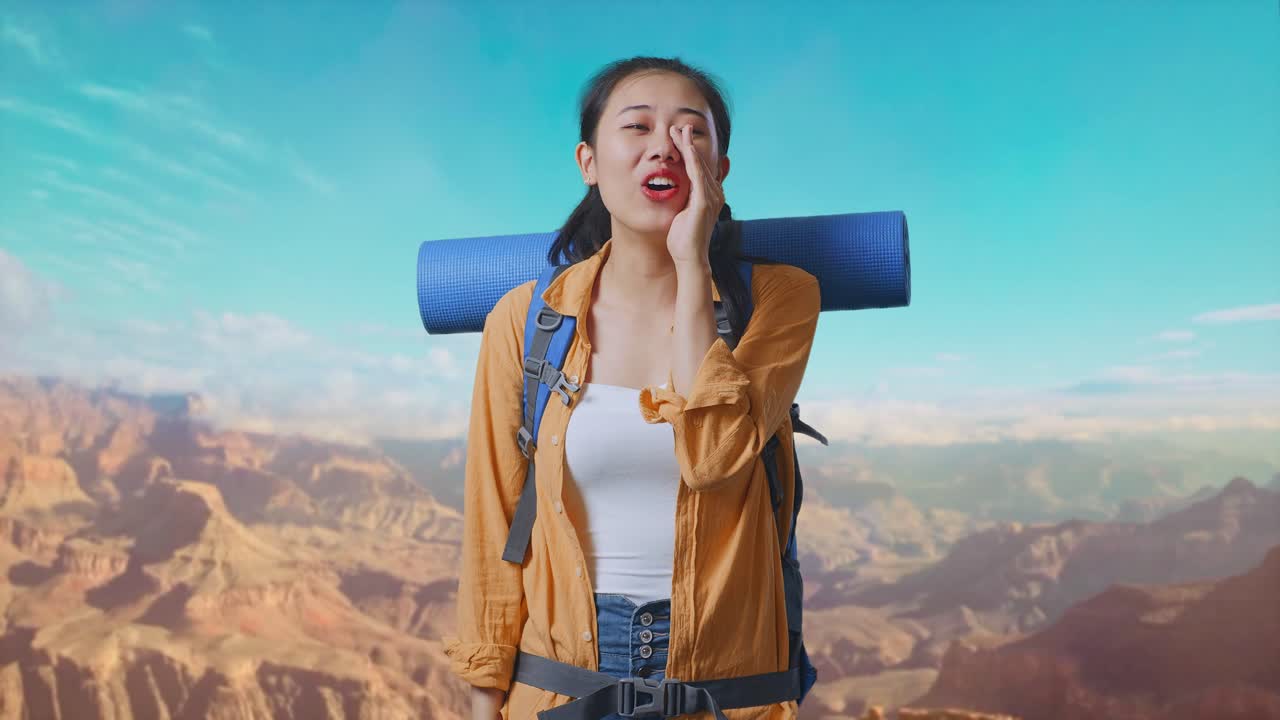 Asian Female Hiker With Mountaineering Backpack Screaming Holding Hands Near Her Mouth While Traveling At The Top Of Mountain