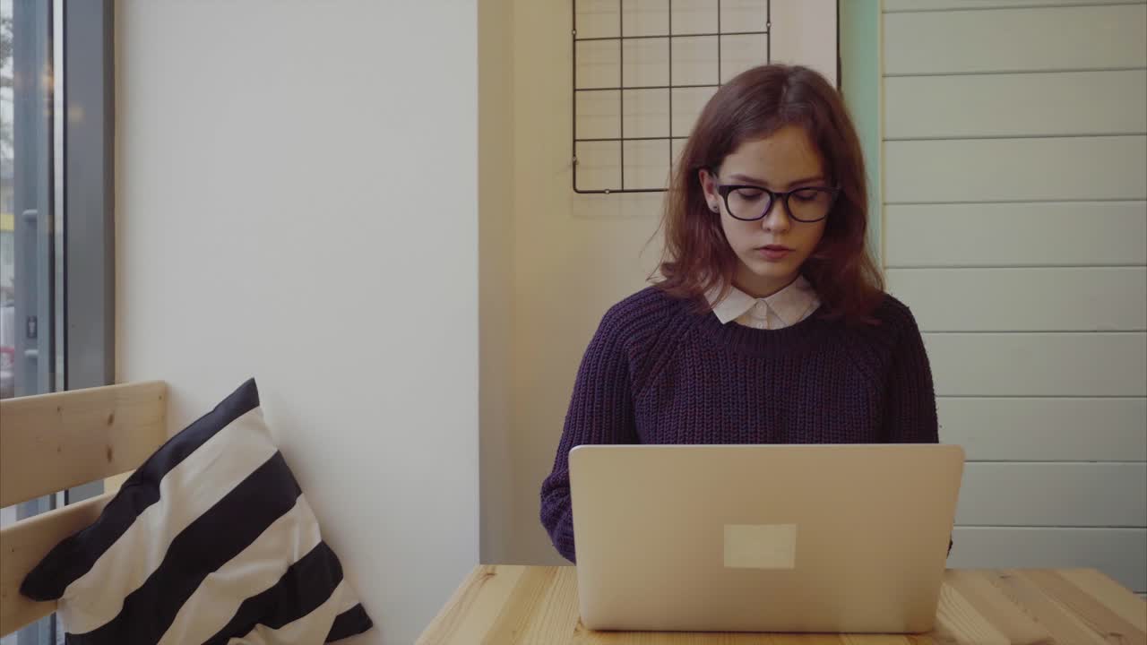 mujer joven trabajando en una computadora portátil en un café