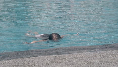 young lady with brown hair swims and dives in pool water