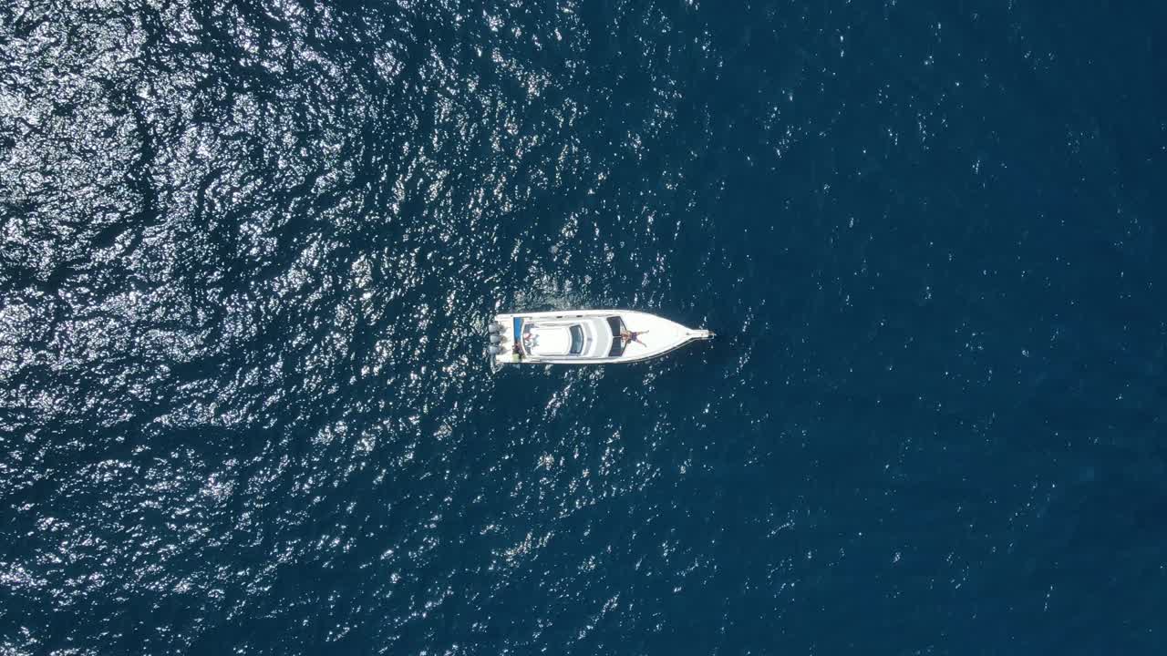 Veduta aerea a volo d'uccello di barche ancorate in acque marine blu intenso, ripresa con drone dall'alto