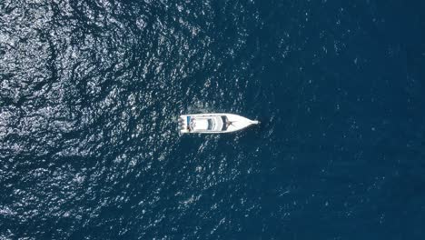 birdseye aerial view of boats anchored in deep blue sea water, high angle drone shot