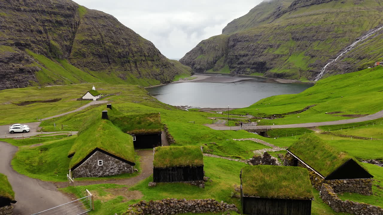 Cinematic aerial view of a dramatic fjord with towering cliffs, black sand river delta, and Atlantic horizon in the Faroe Islands, highlighting raw Nordic wilderness beauty