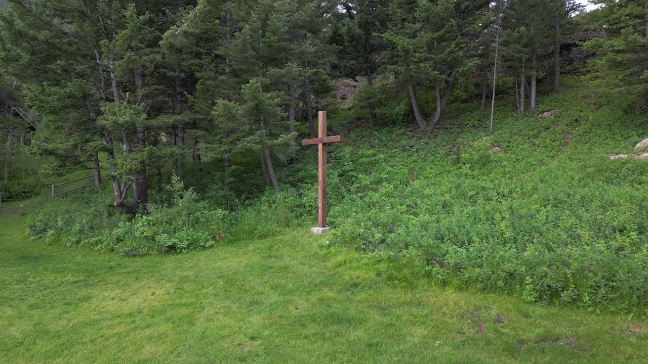 숲 의 가장자리 와 개방 된 초록색 풀 에 있는 나무 로 만든 그리스도인 십자가