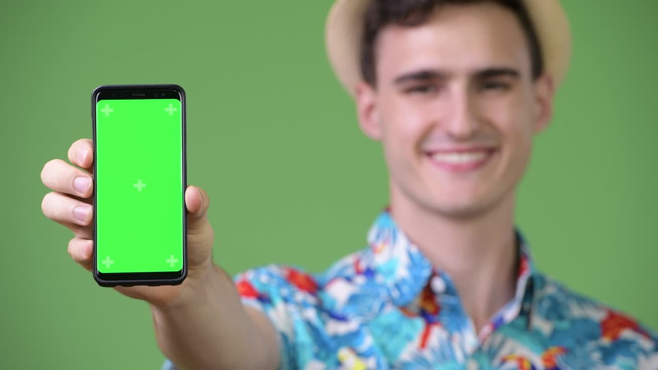joven turista guapo mostrando el teléfono