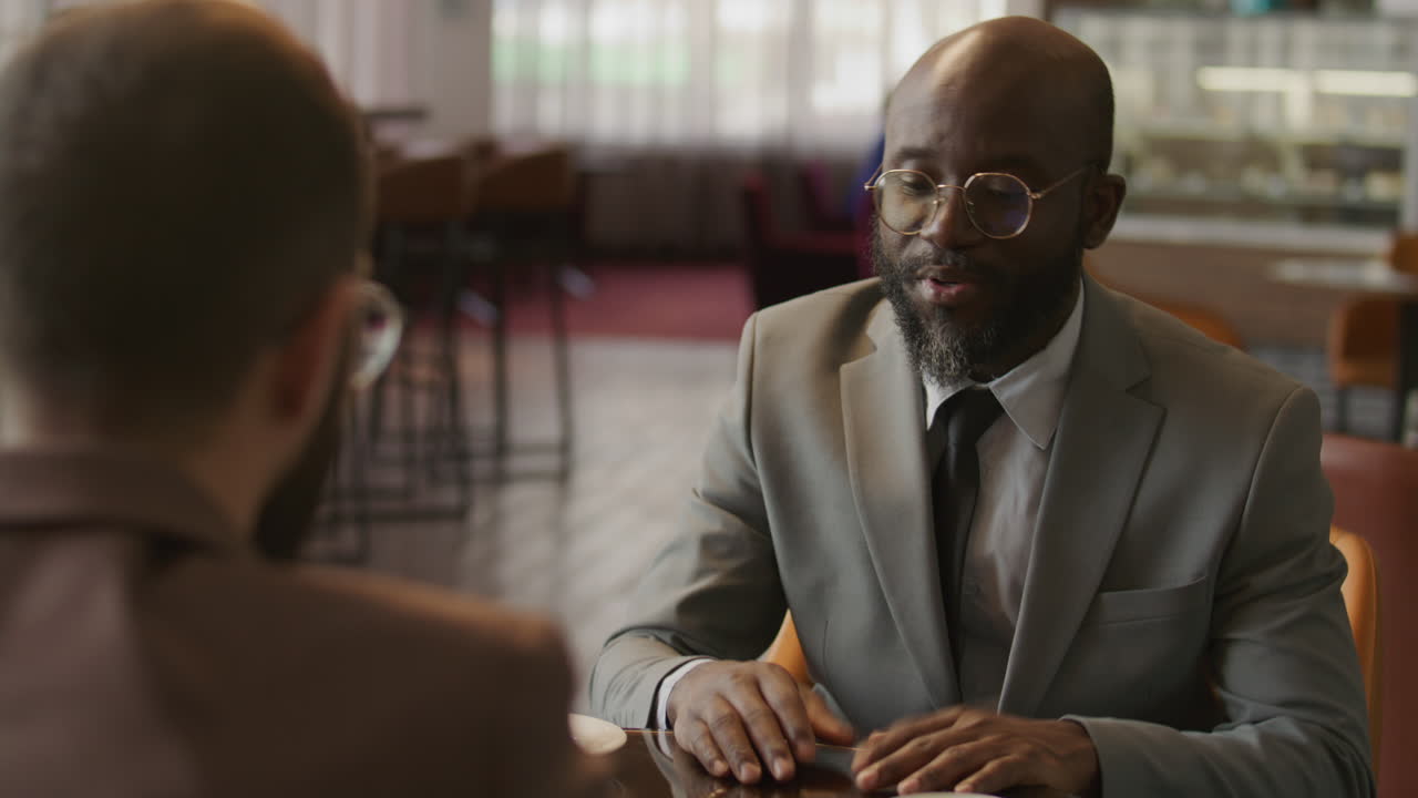 Homme noir serrant la main et discutant avec un partenaire commercial dans le salon d'un hôtel