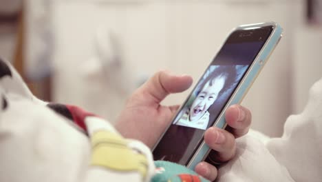 bebé asiático usando teléfonos móviles con mamá en la cama