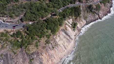 4k aerial view of a rugged coastline with a cliff and a coastal highway