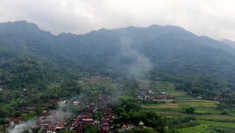 Smoke-rising-from-small-township-of-Indonesia,-aerial-drone-view