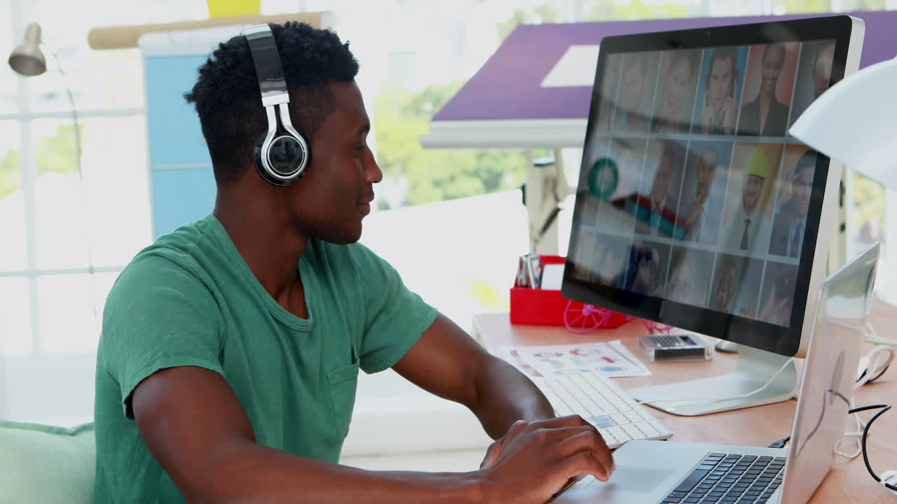 Male executive looking photos on laptop and computer at desk 4k