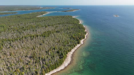 Aerial-ascent-of-forested-lake-shoreline,-Les-Cheneaux-Islands,-Lake-Huron,-Michigan