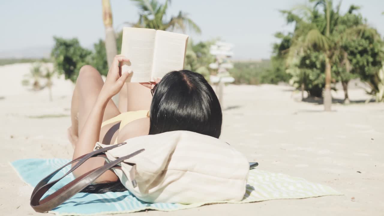 선글라스를 입은 히스패닉 여성이 해변에 누워서 책을 읽고, 복사 공간, 슬로우 모션