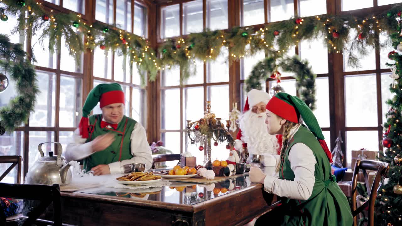 Family dinner at Christmas. Santa Claus celebrating with elves at table