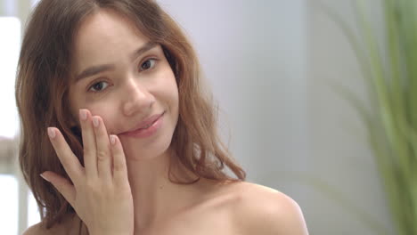 Portrait-young-woman-apply-cosmetic-cream-in-bathroom.-Model-cleaning-skin-face