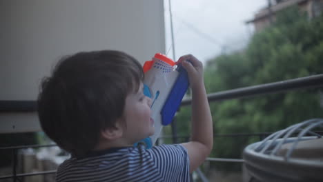 Aufnahmen-Eines-Kleinen-Kaukasischen-Jungen,-Der-Mit-Einem-Wasserpistolenspielzeug-Spielt