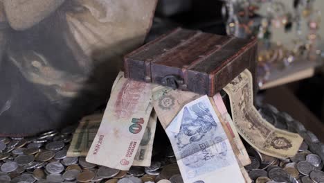 small antique treasure box with old money and pile of coins