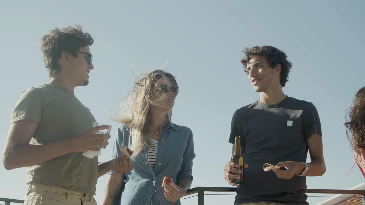 옥상 파티에서 피자를 먹고 맥주를 마시며 함께 이야기하는 근심 없는 친구들