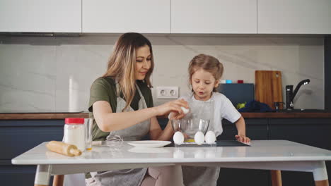 Madre-Con-Hija-Pequeña-Rompe-El-Huevo-En-Un-Recipiente-En-La-Mesa