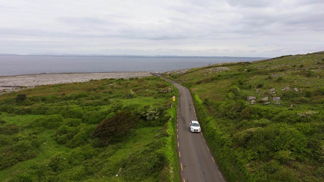 Una strada tortuosa attraversa campi verdi e vivaci, conducendo verso la costa rocciosa dell'Oceano Atlantico. Perfetto per progetti di viaggio o paesaggistici