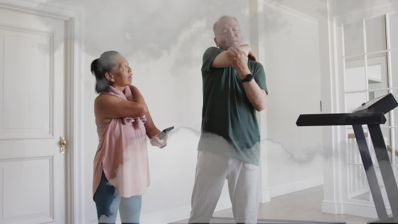 Mature man entering and showing phone, senior woman reaching and following animated fitness guide