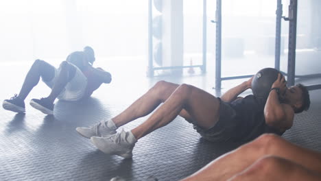 exercising with medicine balls, men doing sit-ups on gym floor