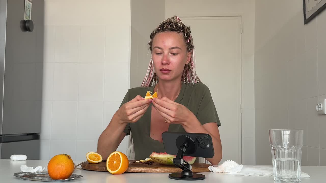 Young Woman Eating and Preparing Fresh Oranges in Kitchen