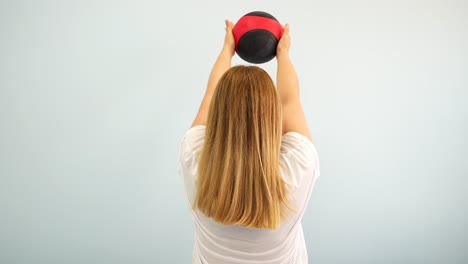 blonde woman raising and holding a medicine ball