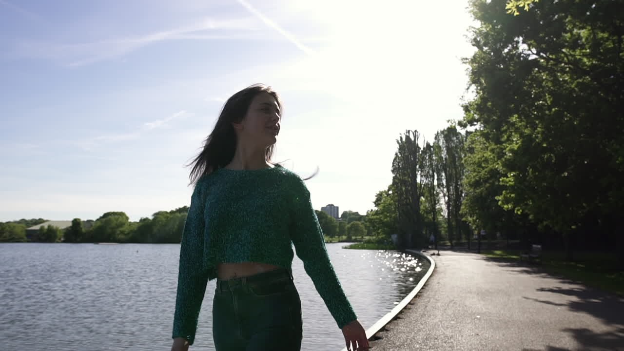 hermosa chica italiana caminando pacíficamente y en un parque tranquilo usando un suéter reluciente en londres, reino unido