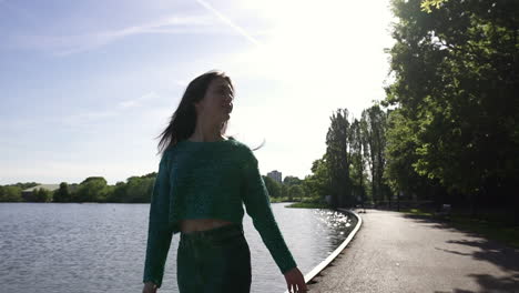 beautiful italian girl walking peacefully and in a tranquil park wearing a shimmery sweater in london, united kingdom