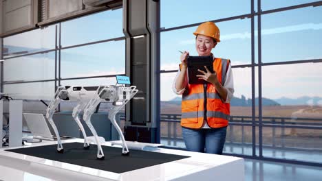 cuerpo lleno de ingeniera asiática con casco de seguridad tomando notas en la tableta y mirando a su alrededor mientras estaba de pie en una fábrica de alta tecnología, analizando el concepto de máquina robótica
