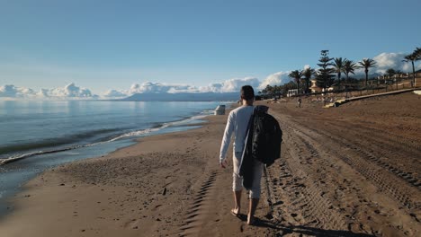 hombre caminando en la playa, perspectiva trasera