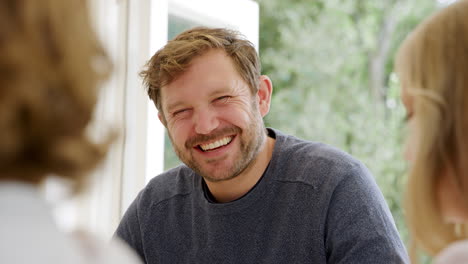 father wearing pyjamas sitting around table at home with daughters enjoying breakfast together