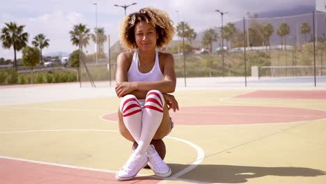 pretty young female athlete sits on basketball