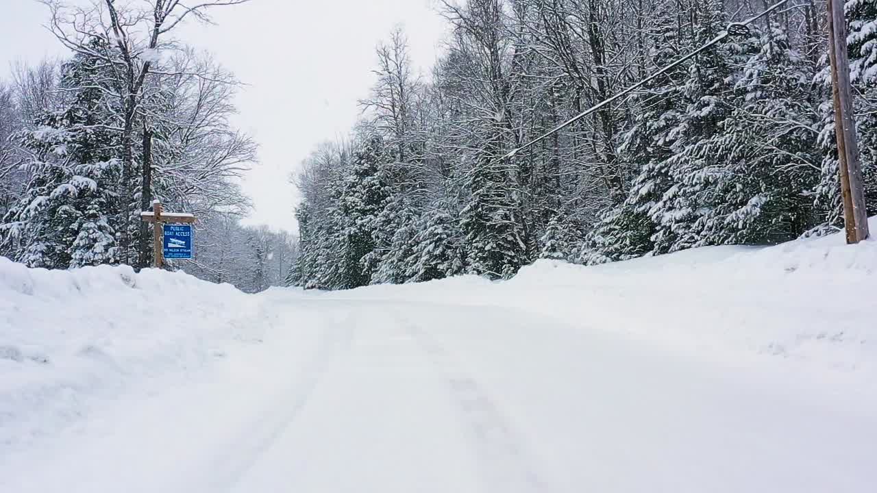 블리자드 슬로우 모션 공중에서 눈 덮인 도로에서 공공 보트 발사 표지판을 지나 낮게 비행