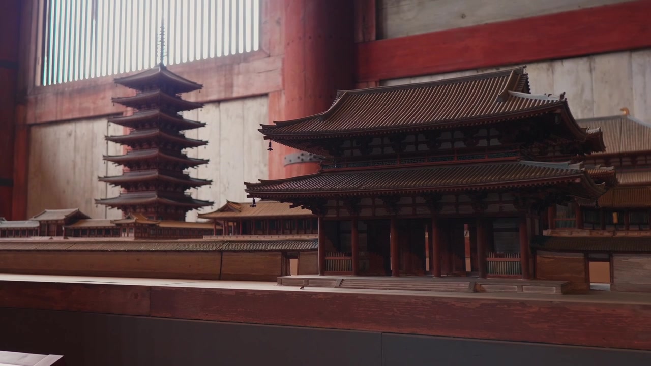 Una pagoda tradicional de cinco pisos se eleva detrás de una puerta de templo roja, mostrando la arquitectura religiosa japonesa clásica.