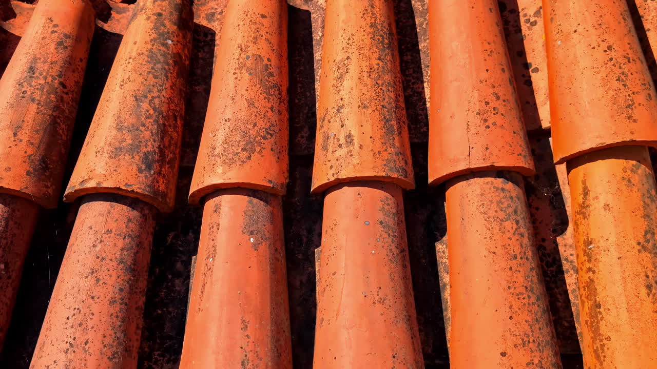 Closeup of orange terracotta roof tiles stacked in pattern, strong texture and shadows