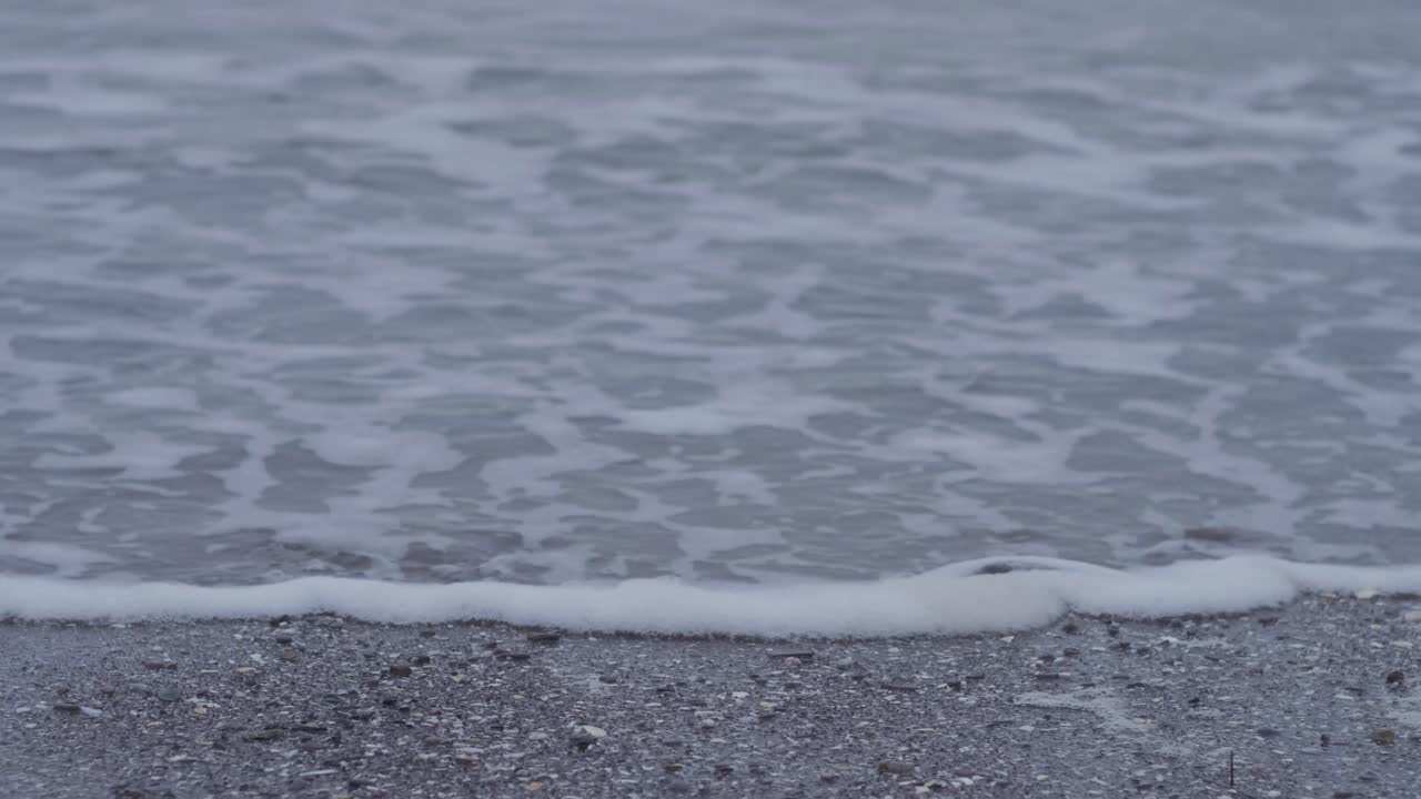 Calm Ocean Waves on a Grey Sandy Beach