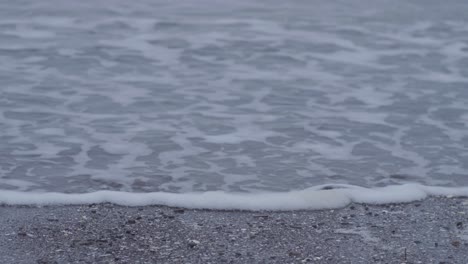calm ocean waves on a grey sandy beach