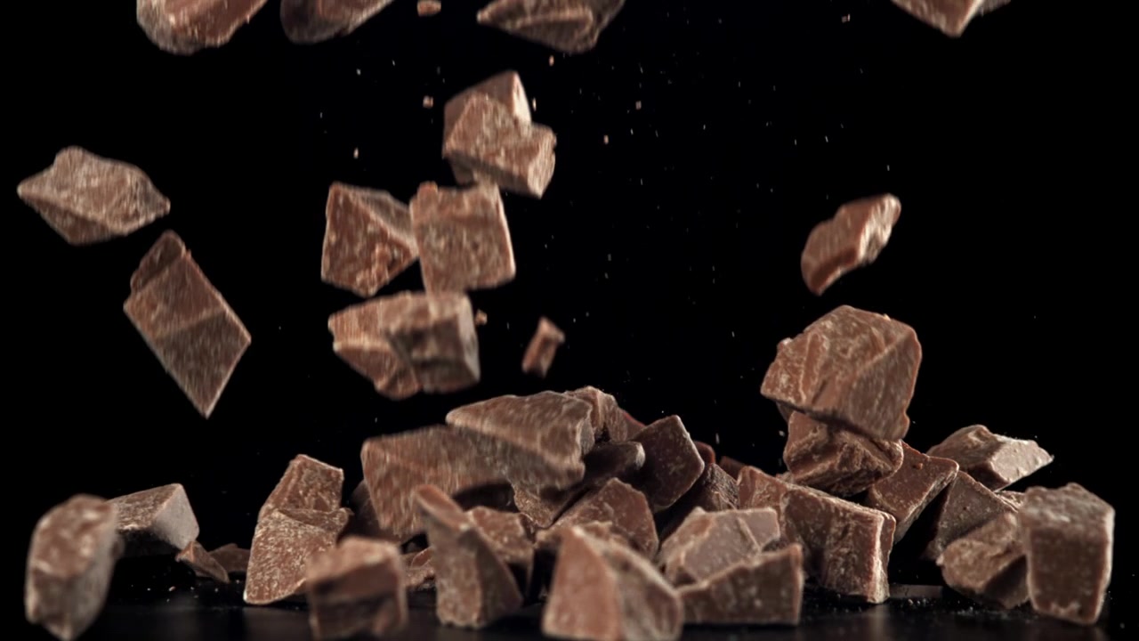 Pezzi di cioccolato che cadono al rallentatore su sfondo nero