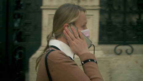 woman in mask talking on mobile when walking in the city